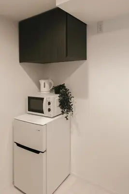 a kitchen with a microwave on top of a refrigerator at Roppongi Designer Apartment Newly built 5 minutes walk to the station in Tokyo