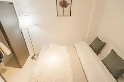 a white bed in a room with a lamp at Roppongi Designer Apartment Newly built 5 minutes walk to the station in Tokyo