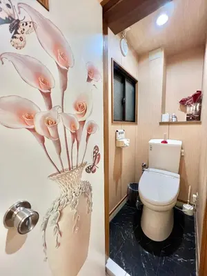 a bathroom with a toilet and a vase with flowers on the wall at \u4e0a\u91ce\u65e5\u5f0f\u6c11\u5bbf in Tokyo
