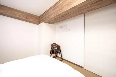 a bedroom with white walls and a bed and a chair at Vacation Inn Omorikaigan in Tokyo