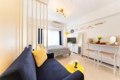 a living room with a blue couch and a kitchen at Felizstay Tokyo in Tokyo