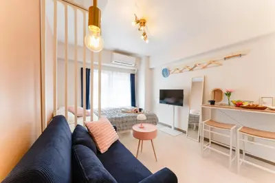a living room with a blue couch and a kitchen at Felizstay Tokyo in Tokyo