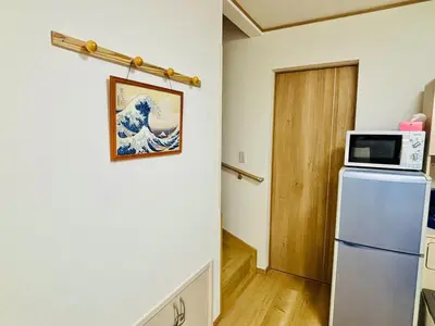 a kitchen with a refrigerator and a microwave on a wall at \u62bc\u4e0a\u30d6\u30ea\u30b9\u30cf\u30a6\u30b9 in Tokyo