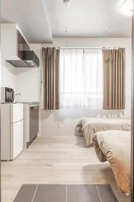 a bedroom with two beds and a kitchen with a window at Marvelous Higashikanda - Vacation STAY 85125v in Tokyo