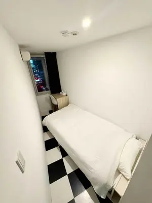 a small bedroom with a bed and a checkered floor at Hotel Alphinaud - Vacation STAY 91089v in Tokyo