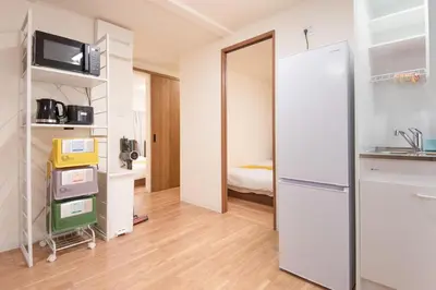 a kitchen with a refrigerator and a room with a bed at Fullhouse 201 in Tokyo