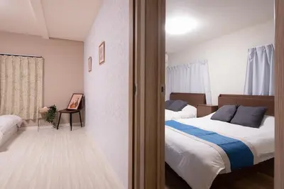a bedroom with two beds and a door to a room at Fullhouse 202 in Tokyo
