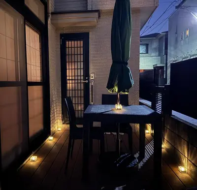 a table with a umbrella on a balcony with lights at Lucky you! TATEISHI in Tokyo
