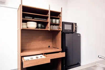 a kitchen with a wooden cabinet next to a refrigerator at \u30b3\u30fc\u30c8\u30cf\u30a6\u30b9\u4e09\u8336 in Tokyo