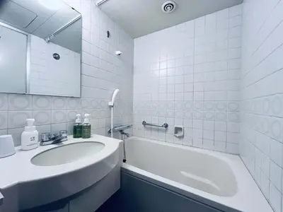 a white bathroom with a sink and a tub and a mirror at Grand Central Hotel in Tokyo