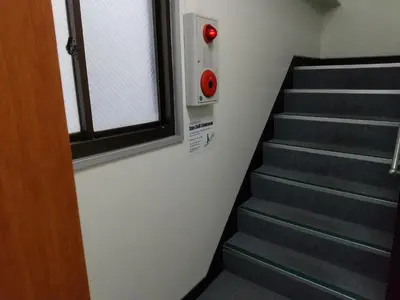 a stairway with a red button next to a window at Stay Chill Shinbashi in Tokyo