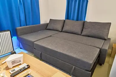 a grey couch in a living room with blue curtains at IZURU Shiba Hamamatsucho 3F in Tokyo