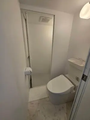 a small bathroom with a toilet and a shower at Port House Honmachi in Tokyo