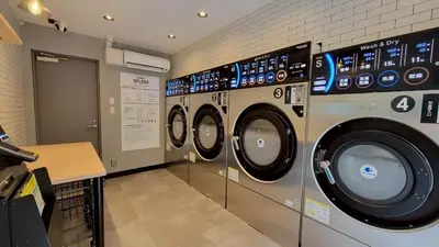 a laundry room with three washing machines in it at Port House Honmachi in Tokyo