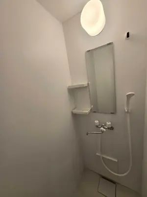 a bathroom with a toilet with a light on the wall at Port House Honmachi in Tokyo