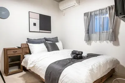a bedroom with a bed with white sheets and a window at Horizon Court Shinjuku in Tokyo