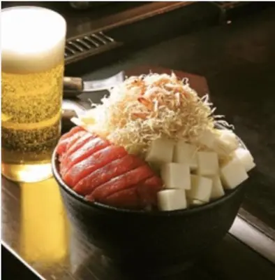 a bowl of sausages and cheese next to a beer at \u53f0\u67713\u4e01\u76ee\u6238\u5efa in Tokyo