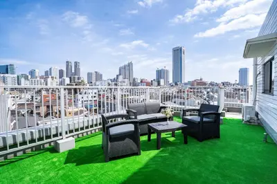 a balcony with green grass and chairs and a city skyline at 6th floor 602 with elevator, 700 meters walk from Nishi-Shinjuku Gochome 4 minutes to Shinjuku, 75 square meters plus 30 square meters of large balcony in Tokyo