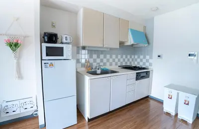 a kitchen with white cabinets and a white refrigerator at 6th floor 602 with elevator, 700 meters walk from Nishi-Shinjuku Gochome 4 minutes to Shinjuku, 75 square meters plus 30 square meters of large balcony in Tokyo