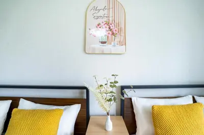 a mirror above a bed with a vase of flowers at 6th floor 602 with elevator, 700 meters walk from Nishi-Shinjuku Gochome 4 minutes to Shinjuku, 75 square meters plus 30 square meters of large balcony in Tokyo