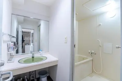a white bathroom with a sink and a shower at 6th floor 602 with elevator, 700 meters walk from Nishi-Shinjuku Gochome 4 minutes to Shinjuku, 75 square meters plus 30 square meters of large balcony in Tokyo