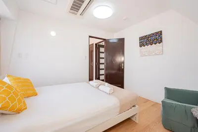 a white bedroom with a bed and a couch at Akabanestay A \u5fd7\u8302 in Tokyo