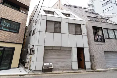 a white building with a garage door on a street at Maison Miyashita in Tokyo