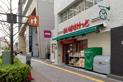a man walking past a grocery store on a street at Maison Miyashita in Tokyo