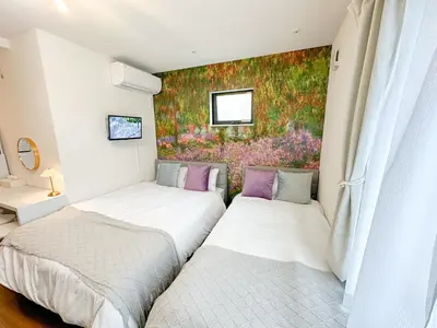 two beds in a room with a painting on the wall at Hotel Ikebukuro Fine Coat in Tokyo