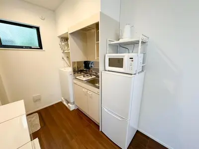 a small kitchen with a white refrigerator and a microwave at Hotel Ikebukuro Fine Coat in Tokyo