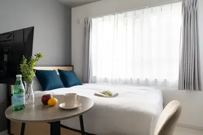 a bedroom with a bed with a table and a window at \u30ea\u30a2\u30e9\u30a4\u30ba\u897f\u5c0f\u5c71 in Tokyo