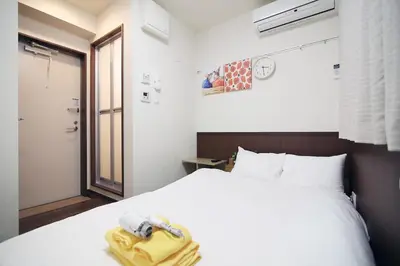 a bedroom with a white bed with a phone on it at Central Shinjuku, Near Train Station, Quiet Area, No Stairs, Room 102 in Tokyo
