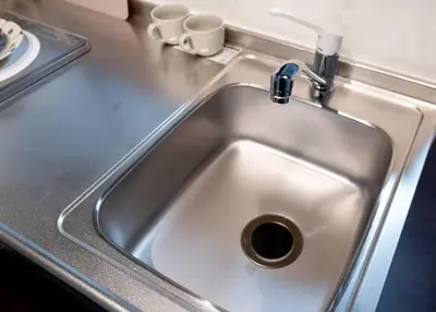 a sink in a kitchen with two cups on a counter at ohayo\u4e21\u56fd in Tokyo