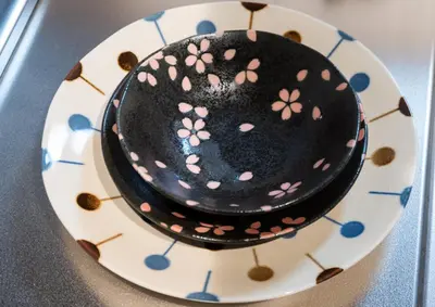 a black cake with pink flowers on a plate at ohayo\u4e21\u56fd in Tokyo