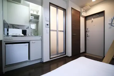 a kitchen with white cabinets and a bed in a room at Close to Station, Quiet Area, Central Shinjuku, Room 203 in Tokyo