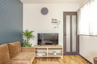 a living room with a couch and a flat screen tv at Nogata Station 3 minutes on foot , 15 minutes to Shinjuku in Tokyo
