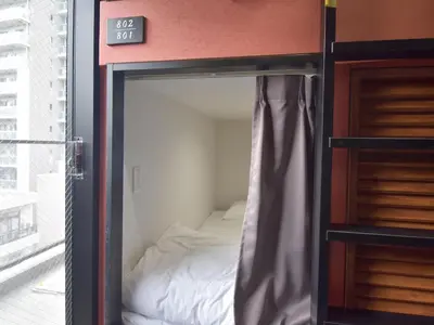 a bedroom with a bed inside of a room at HOTEL WINDS ASAKUSA Capsule Inn \u6d45\u8349 in Tokyo