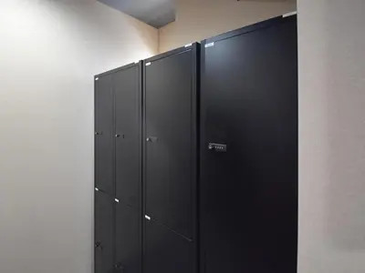 a row of black lockers in a room at HOTEL WINDS ASAKUSA Capsule Inn \u6d45\u8349 in Tokyo
