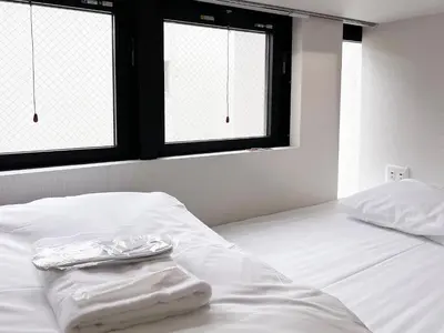 a white bed with two towels sitting on top of it at HOTEL WINDS ASAKUSA Capsule Inn \u6d45\u8349 in Tokyo