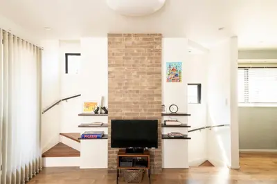 a living room with a brick wall and a tv at Zuzu & Gizmo in Tokyo