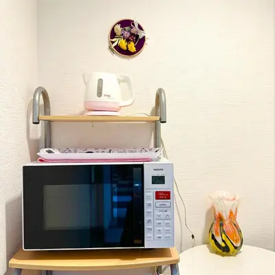 a microwave sitting on a table with a shelf above it at ookubo hills Room for 2 located in Shinjuku area in Tokyo