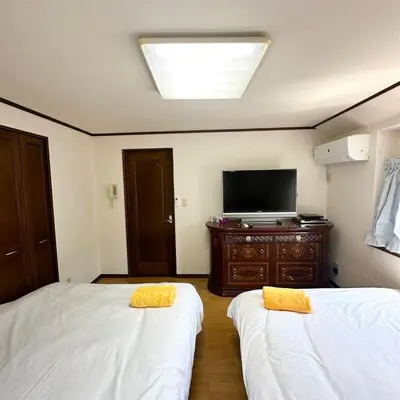 a room with two beds and a tv on a dresser at ookubo hills Unique 3 Bedroom House in Shinjuku area in Tokyo