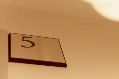 a clock on a wall with the number five at Asakusa Premium Stay \u5f69-Irodori- in Tokyo