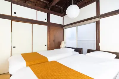 two beds in a room with large windows at The Guest House Nagomi in Tokyo