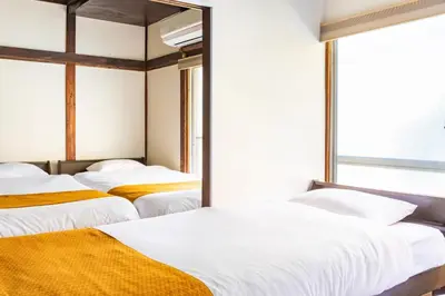 two beds in a room with a window at The Guest House Nagomi in Tokyo