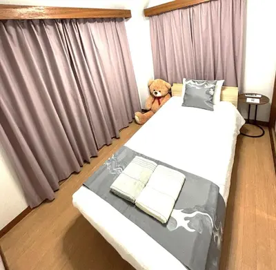 a teddy bear sitting on a bed in a bedroom at Lucky house west Kitasenju in Tokyo