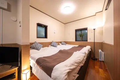 a bedroom with a large bed and a flat screen tv at Nestry \u6d45\u8349 yuuan Sakura102 in Tokyo
