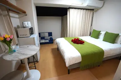 a bedroom with a bed with a green blanket and flowers on it at 406Room,With elevator, 700m 4 min walk from Nishi-Shinjuku 5-chome, direct access to Shinjuku, 28 sqm in Tokyo