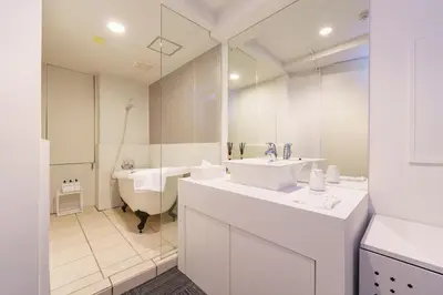 a white bathroom with two sinks and a tub and a bath tub at feel Akihabara STAY in Tokyo
