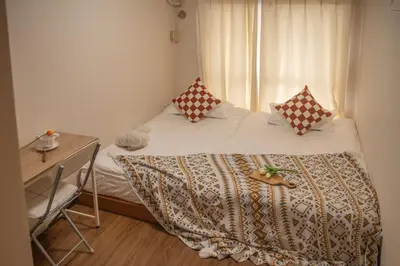 a bedroom with a bed with a desk and a window at Shinjuku 2 stops Higashinakano three people in Tokyo